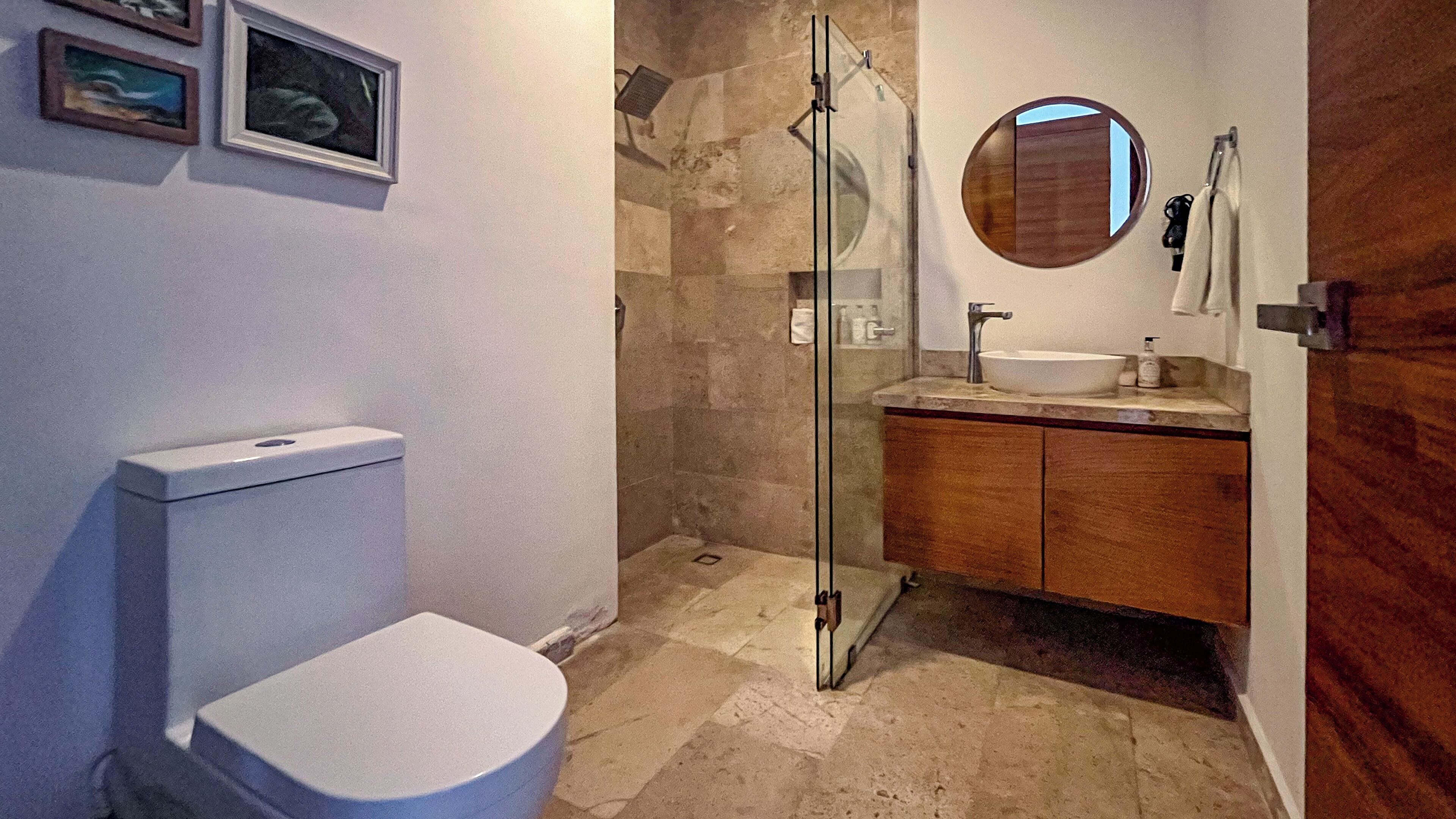Ein Badezimmer mit Toilette, einer Duschkabine, einem Waschbecken und einem Spiegel.