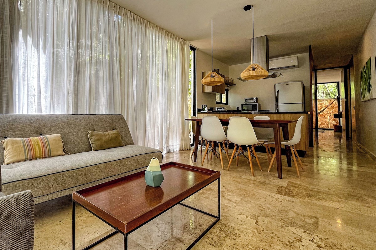 Un salon moderne avec un canapé, une table basse et un coin repas avec des chaises.