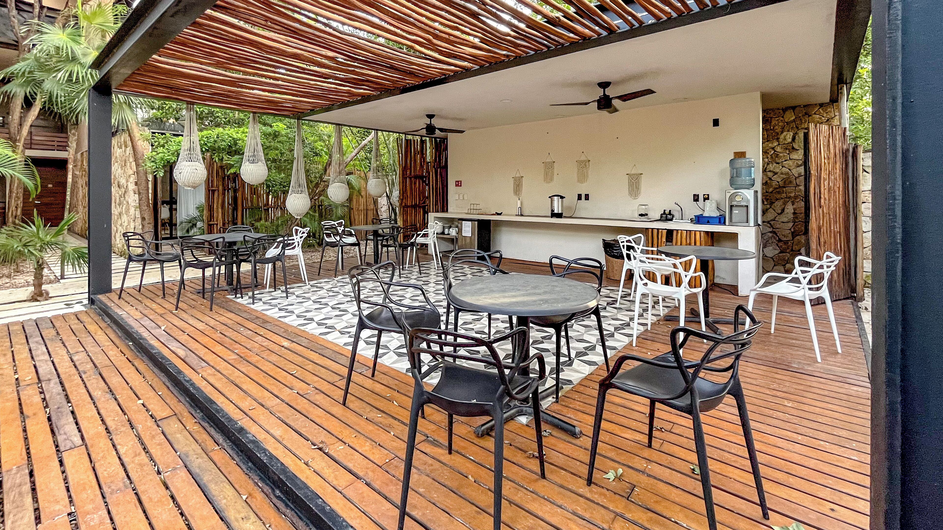 An outdoor patio with wooden flooring, black and white chairs, and a central round table.