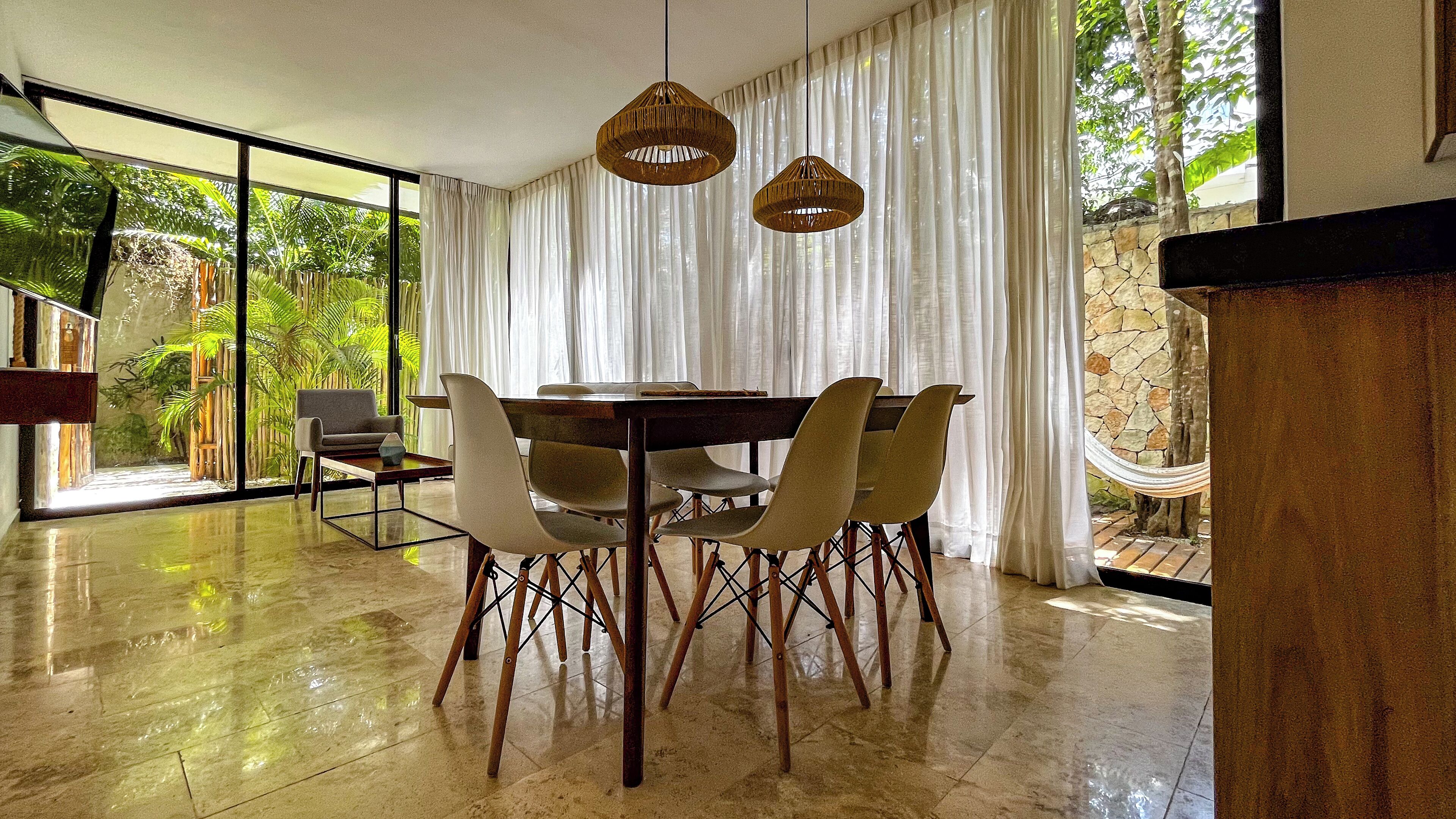A dining area with a round table, six chairs, and two hanging pendant lights.
