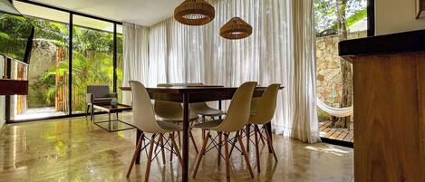 A dining area with a round table, six chairs, and two hanging pendant lights.