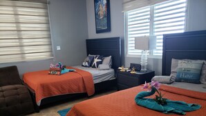 A hotel room with two beds, a brown armchair, a nightstand with a lamp, and a painting on the wall. - Caribbean getaway aguadilla (Aguadilla Pueblo)