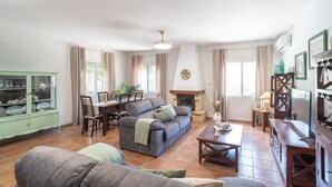 Ein Wohnzimmer mit einer Couch, einem Esstisch, Stühlen, einem Kamin und einem Fernseher.