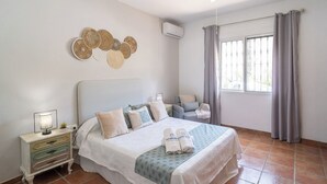 Ein Schlafzimmer mit Bett, Nachttisch, Wanddekoration und einem Fenster mit Vorhängen.