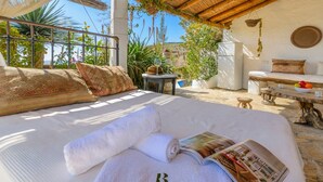 A bed with rolled towels and a magazine, a small table with a basket, and a view of greenery and hills. - The Hunting Lodge Alcaucín by Ruralidays (Málaga)