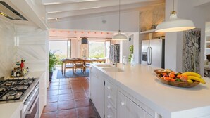 A modern kitchen with a large island, a dining area with a table and chairs, and a view of the outdoors. - The Hunting Lodge Alcaucín by Ruralidays (Málaga)