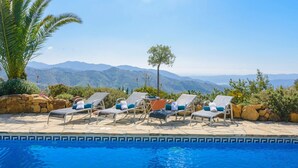 A poolside area with lounge chairs and a view of mountains. - The Hunting Lodge Alcaucín by Ruralidays (Málaga)