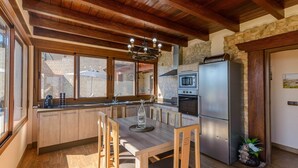 Una cocina con armarios de madera, horno empotrado, refrigerador y comedor con mesa y sillas de madera.