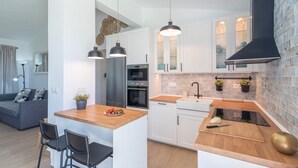 A modern kitchen with white cabinets, a wooden island, and pendant lighting. - Cortijo Entre Pueblos Cómpeta by Ruralidays (Málaga)