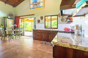 A kitchen with wooden cabinets, a granite countertop, and a view of the outdoors.
