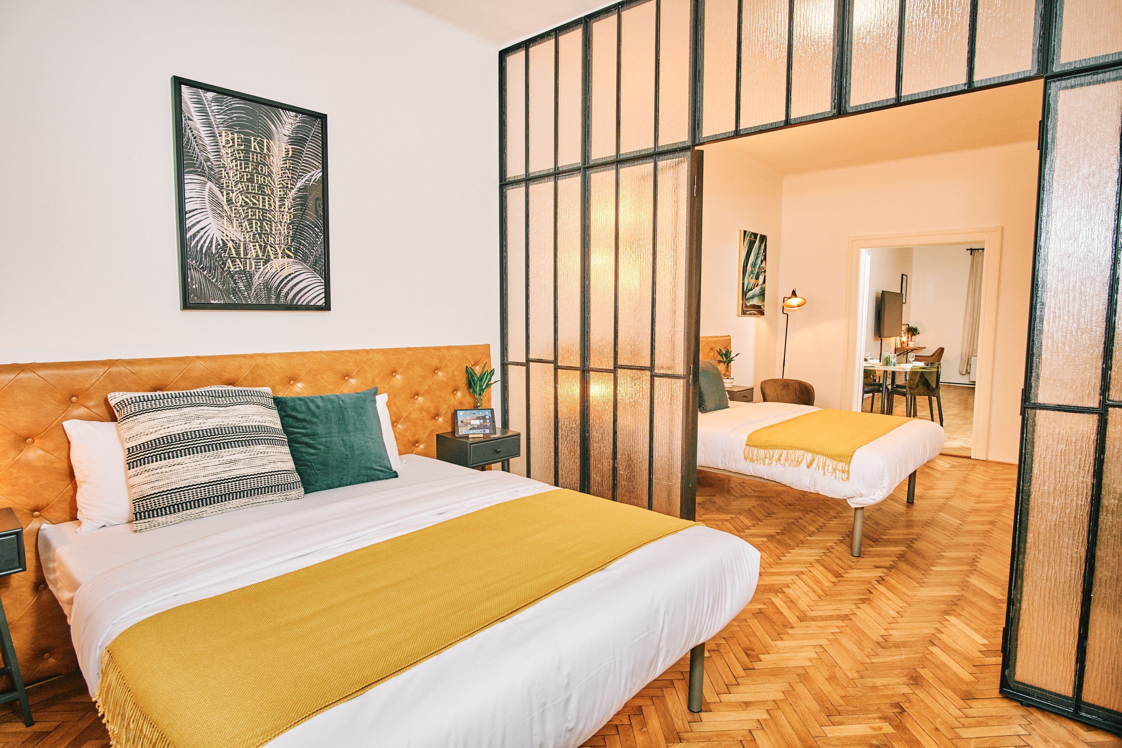 Hotellihuone, jossa on suuri sänky, yöpöytä, peili ja näkymä käytävälle.