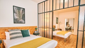 A hotel room with a large bed, a bedside table, a nightstand, a mirror, and a view of the hallway. - CAMŌ ROOMS - Boutique Aparthotel (Prague)