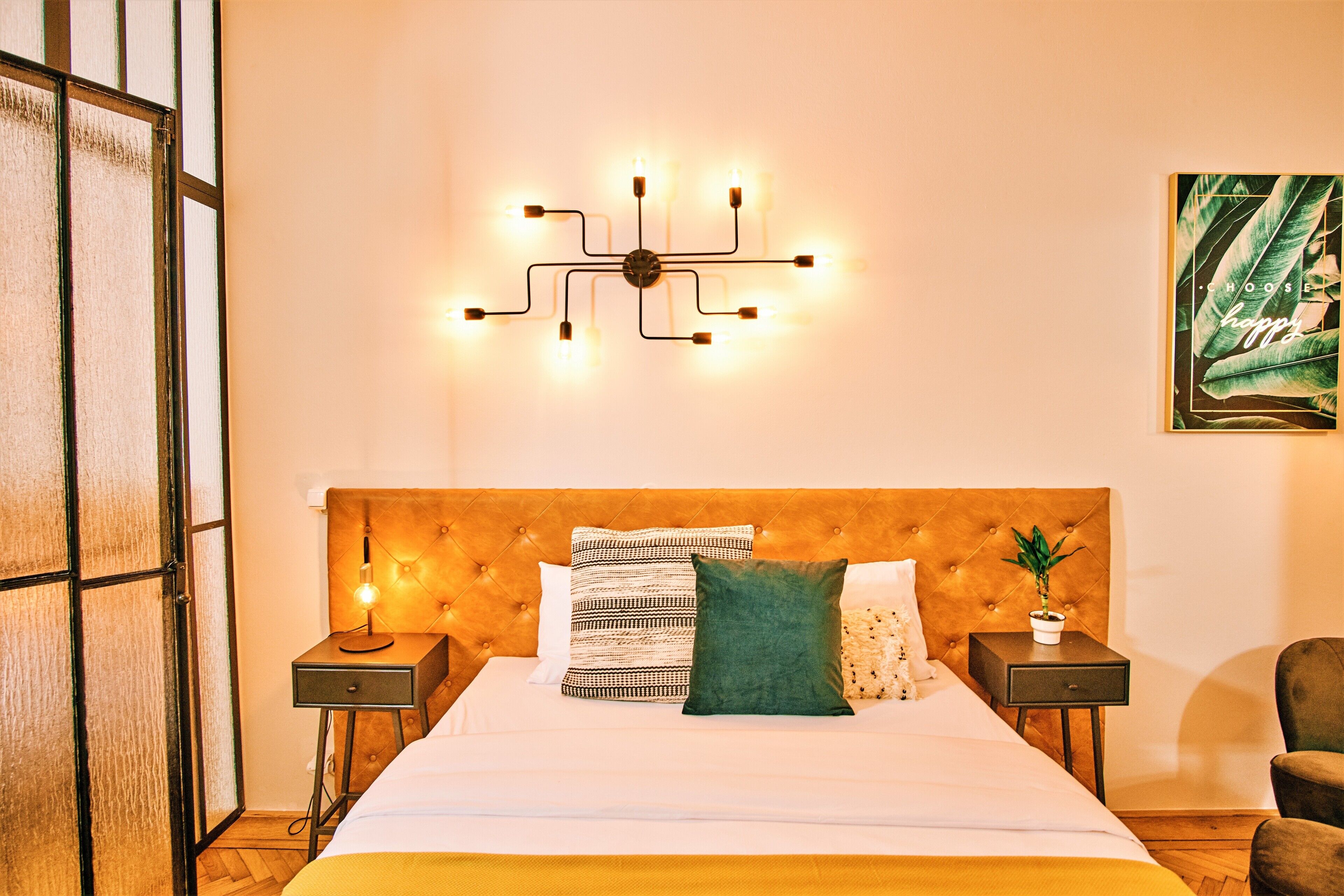 Quarto de hotel bem organizado com uma cama grande, luminária fixada na parede e uma obra de arte emoldurada.