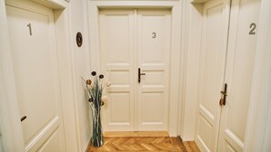 A hallway with three doors, each marked with a number. - CAMŌ ROOMS - Boutique Aparthotel (Prague)
