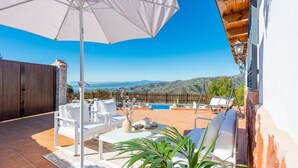 A patio with white furniture, a pool, and a view of hills. - Villa Francisco Torrox by Ruralidays (Málaga)