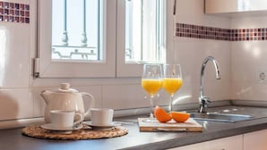 A kitchen with a white teapot, two cups, and two glasses of orange juice on a wooden board. - Villa Francisco Torrox by Ruralidays (Málaga)