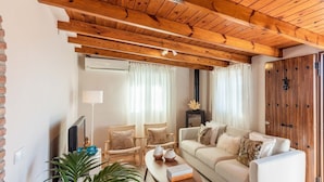 A cozy living room with a wooden ceiling, a sofa set, two armchairs, a coffee table, and a TV. - Villa Francisco Torrox by Ruralidays (Málaga)