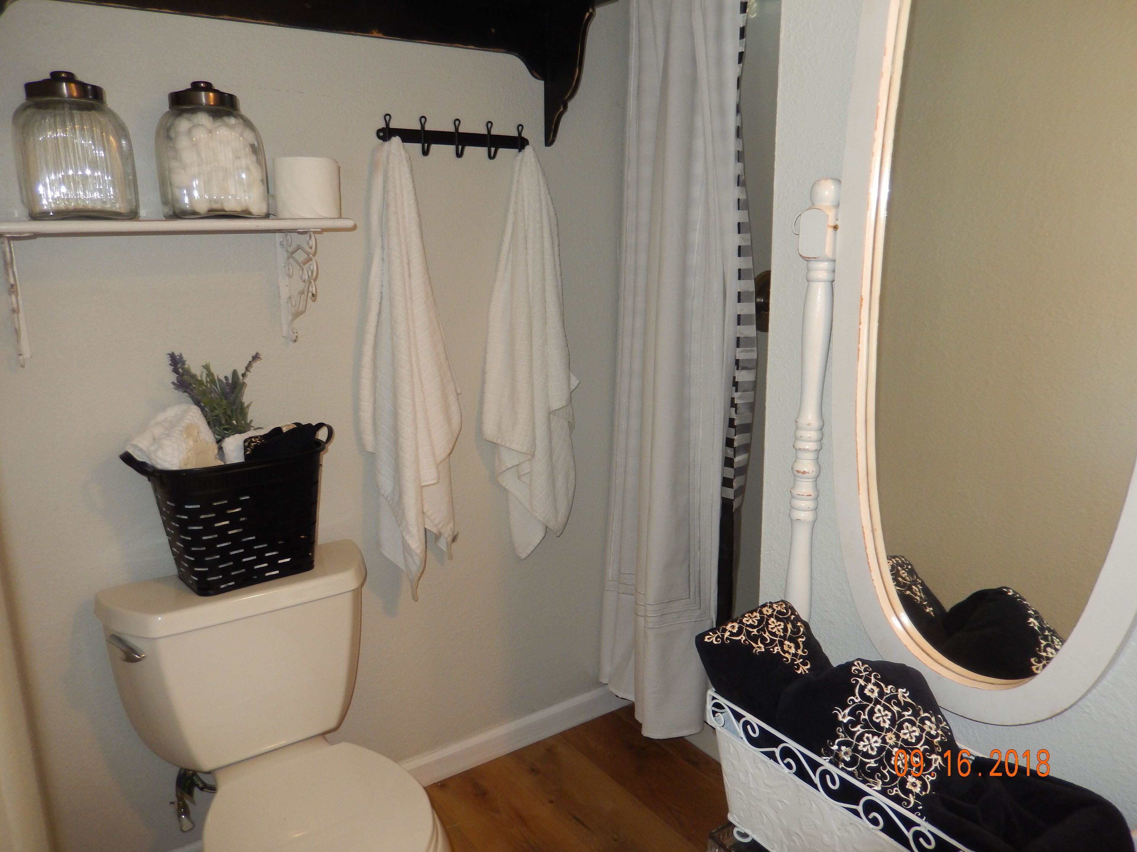 Une salle de bain comprenant des toilettes, un lavabo, un miroir et une étagère avec des pots.
