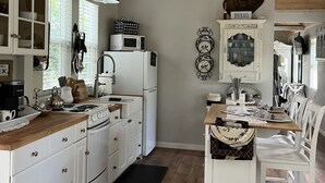 A kitchen with wooden cabinets, a microwave, a stove, and a dining area with a table and chairs.