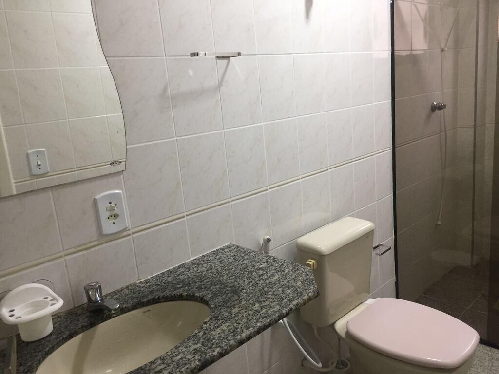 Un baño con lavamanos de encimera de granito, inodoro y cabina de ducha de vidrio.