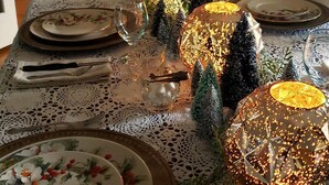 A dining table set with plates, glasses, and a centerpiece.