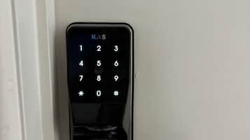 A modern electronic door lock with a keypad and a push button.
