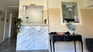 Un área de recepción con mostrador de mármol, una mesa consola negra y una lámpara colgante roja.