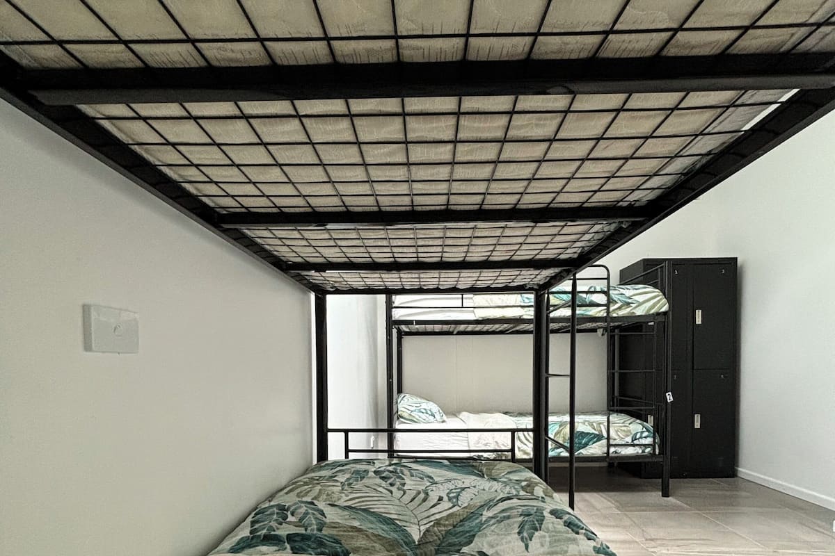Une chambre de dortoir avec des lits superposés, un plafond carrelé et un mur uni.