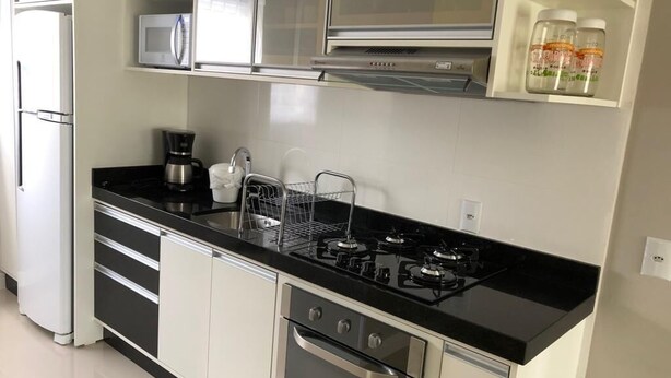 A modern kitchen with a black countertop, stainless steel appliances, and white cabinetry.