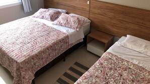 A bedroom with a bed, a nightstand, and a window with curtains.