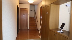 A hallway with wooden flooring, a wooden door, a staircase, and a desk with a computer monitor. - Pop Culture House (Takayama)
