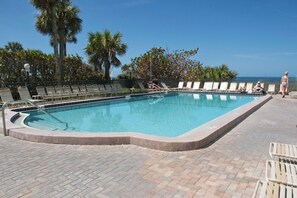 Relax by the pool surrounded by lush trees and lounge chairs.