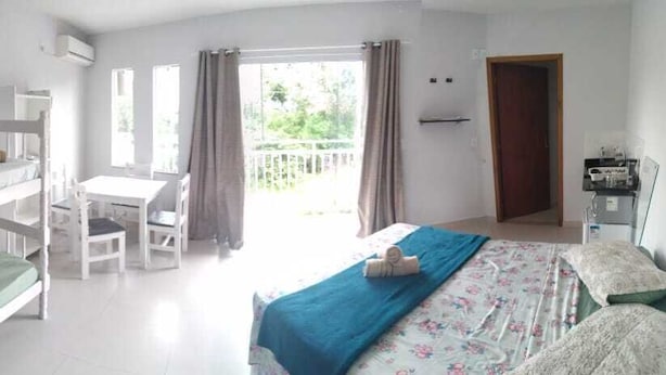 A bedroom with bunk beds, a desk, and a chair. There is a balcony with curtains. - Bela Catarina - Penha - Beto Carrero (Penha)