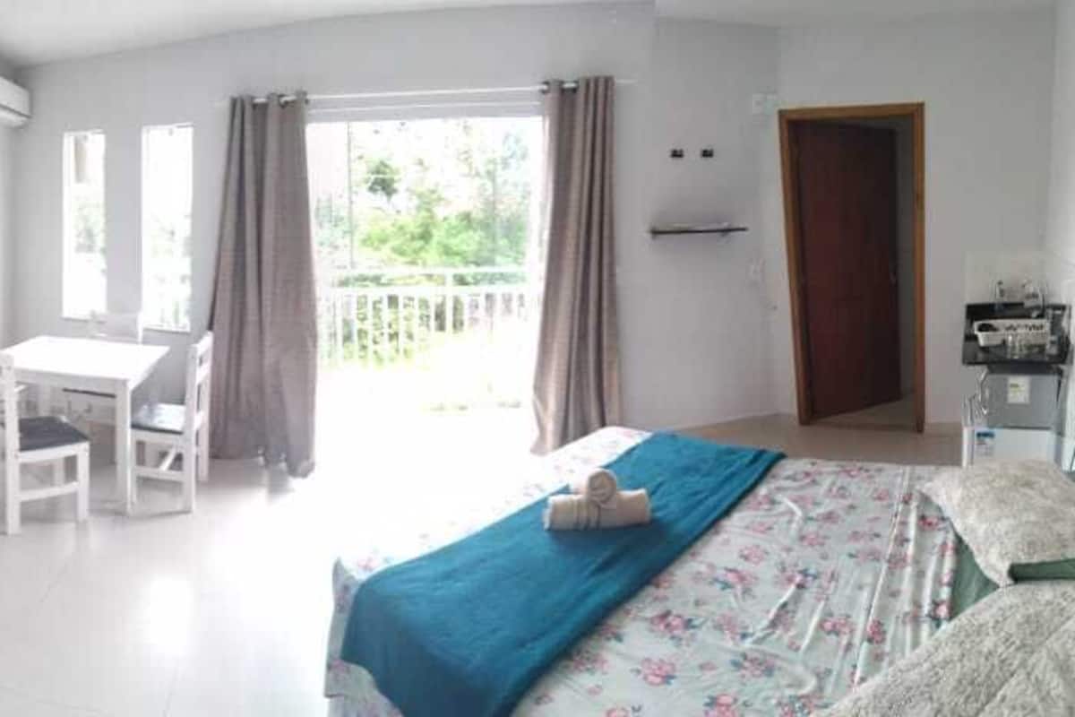 A bedroom with bunk beds, a desk, and a chair. There is a balcony with curtains.