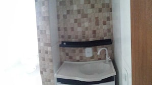 A small bathroom with a tiled backsplash, a white sink, and a black shelf. - Bela Catarina - Penha - Beto Carrero (Penha)