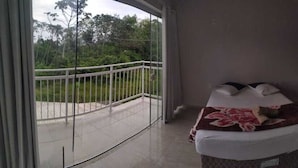 A bedroom with a bed, a small bedside table, a TV, and a balcony with a railing. - Bela Catarina - Penha - Beto Carrero (Penha)