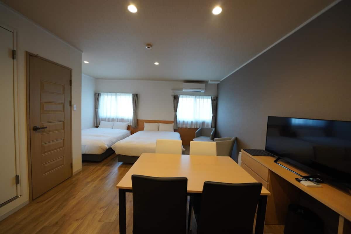 Ett hotellrum med en säng, ett skrivbord med en tv och en matplats med stolar.
