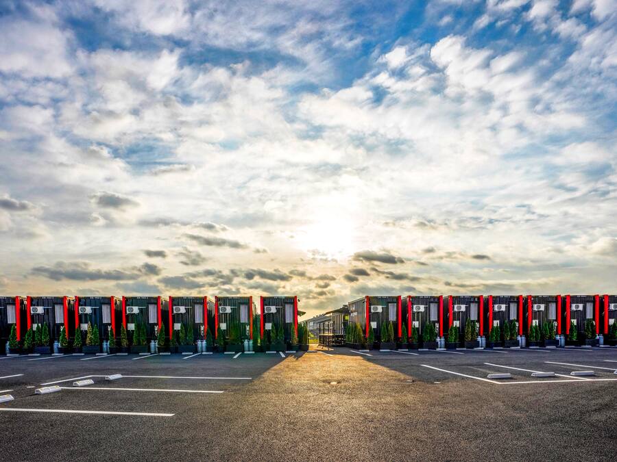 A parking lot with multiple rows of fuel pumps, each with a red vertical stripe.