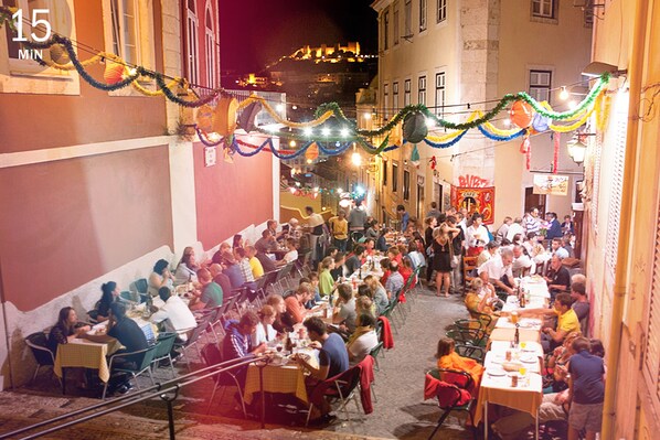Un área de comedor al aire libre con mesas y sillas, rodeada de edificios.