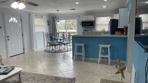 A modern kitchen with a blue accent wall, white bar stools, and a ceiling fan. - WALK TO BEACH ACCESS! DOG FRIENDLY PROPERTY! (Englewood)
