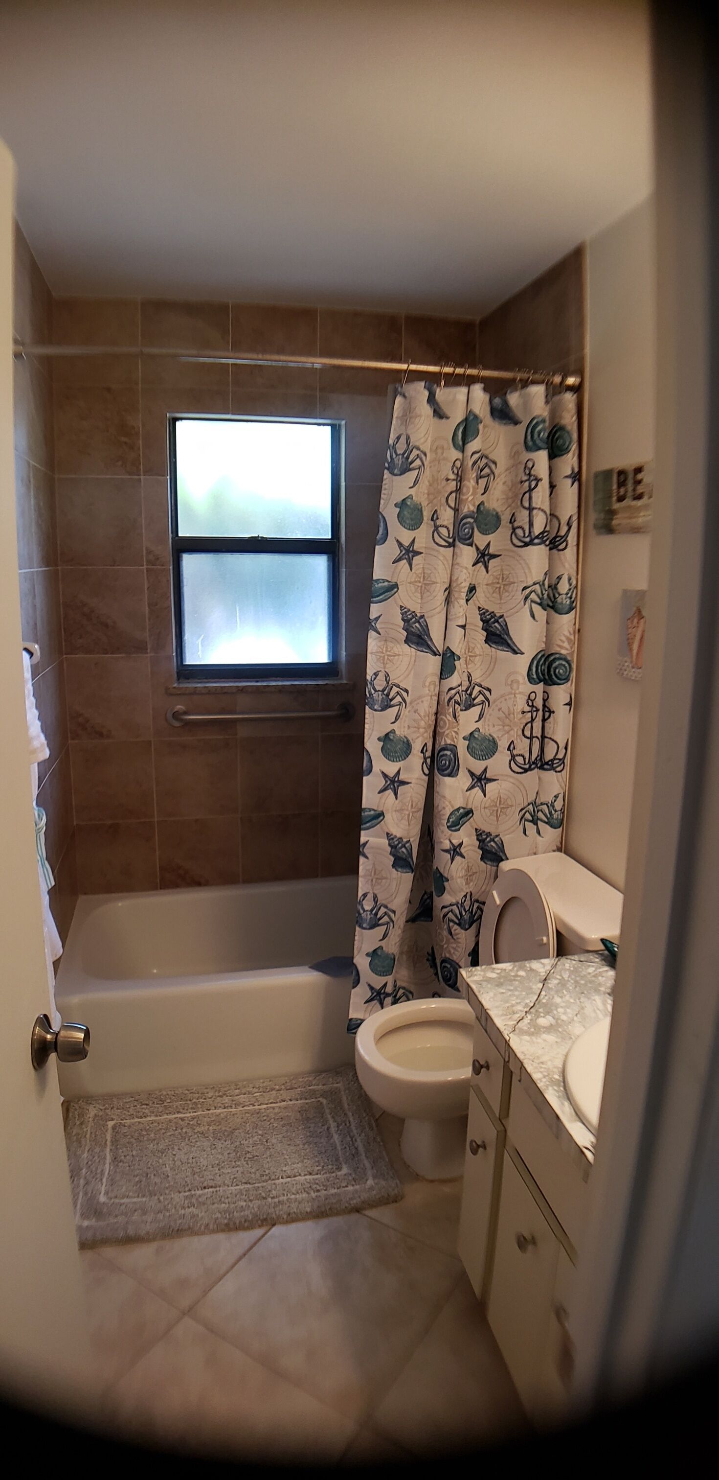Une salle de bain avec une baignoire, des toilettes et une fenêtre.