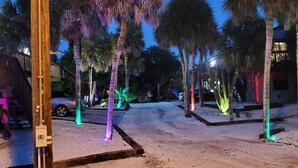 A street lined with palm trees and a building with a lit sign. - WALK TO BEACH ACCESS! DOG FRIENDLY PROPERTY! (Englewood)