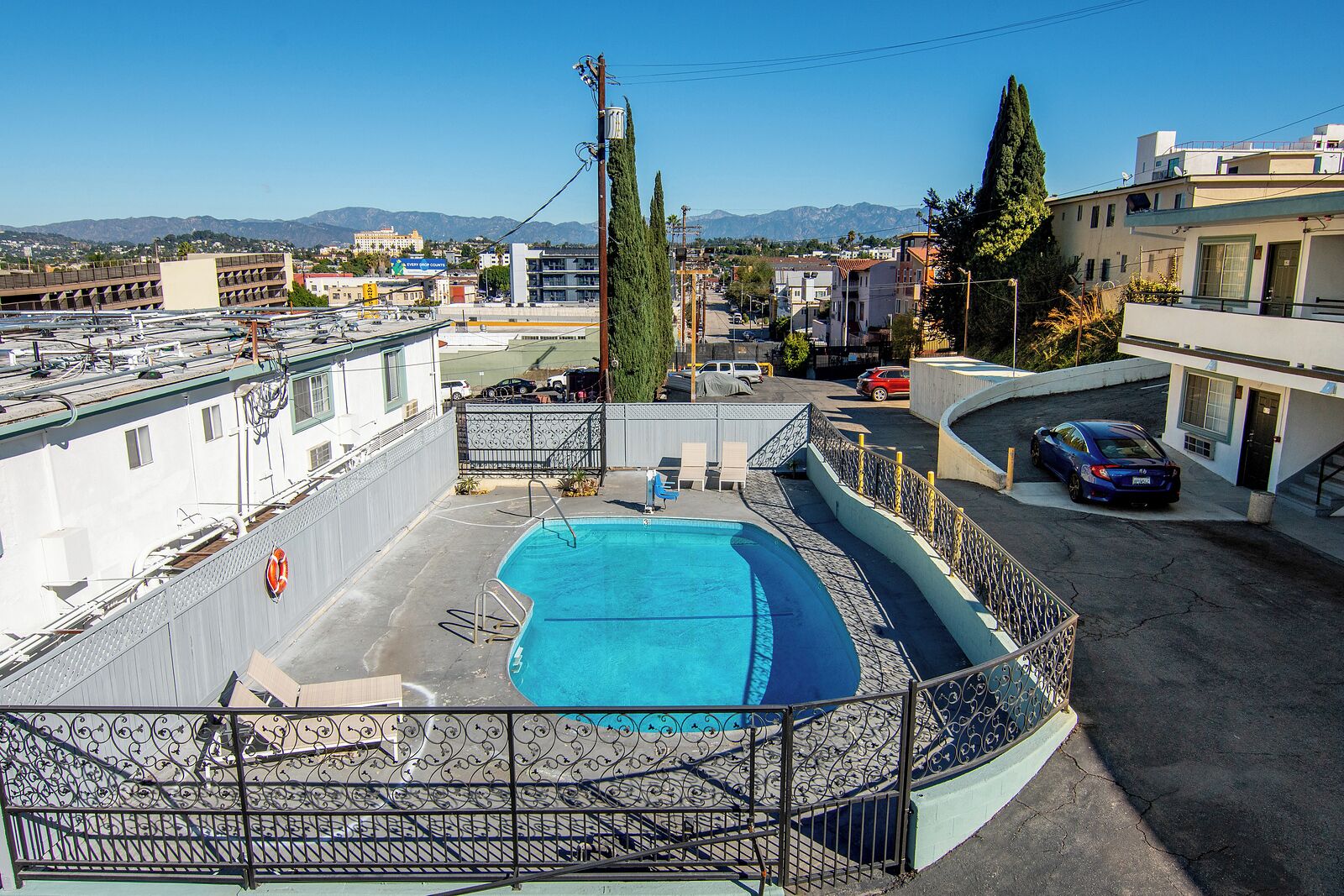 A rooftop pool with a view of the cityscape and mountains in the background.