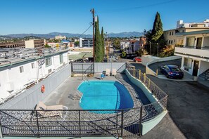 A rooftop pool with a view of the cityscape and mountains in the background.