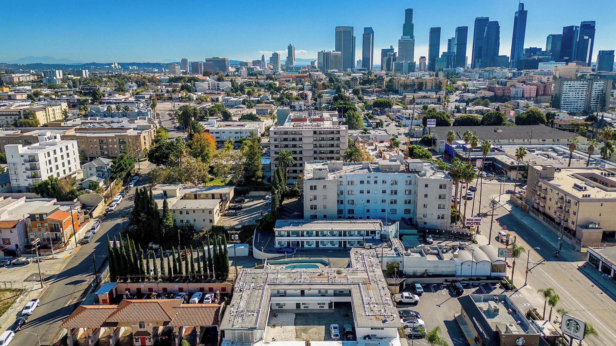A hotel with multiple floors, a rooftop pool, and a view of the city skyline.
