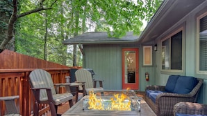 Un patio con una chimenea, deck de madera, mobiliario de mimbre y una puerta.