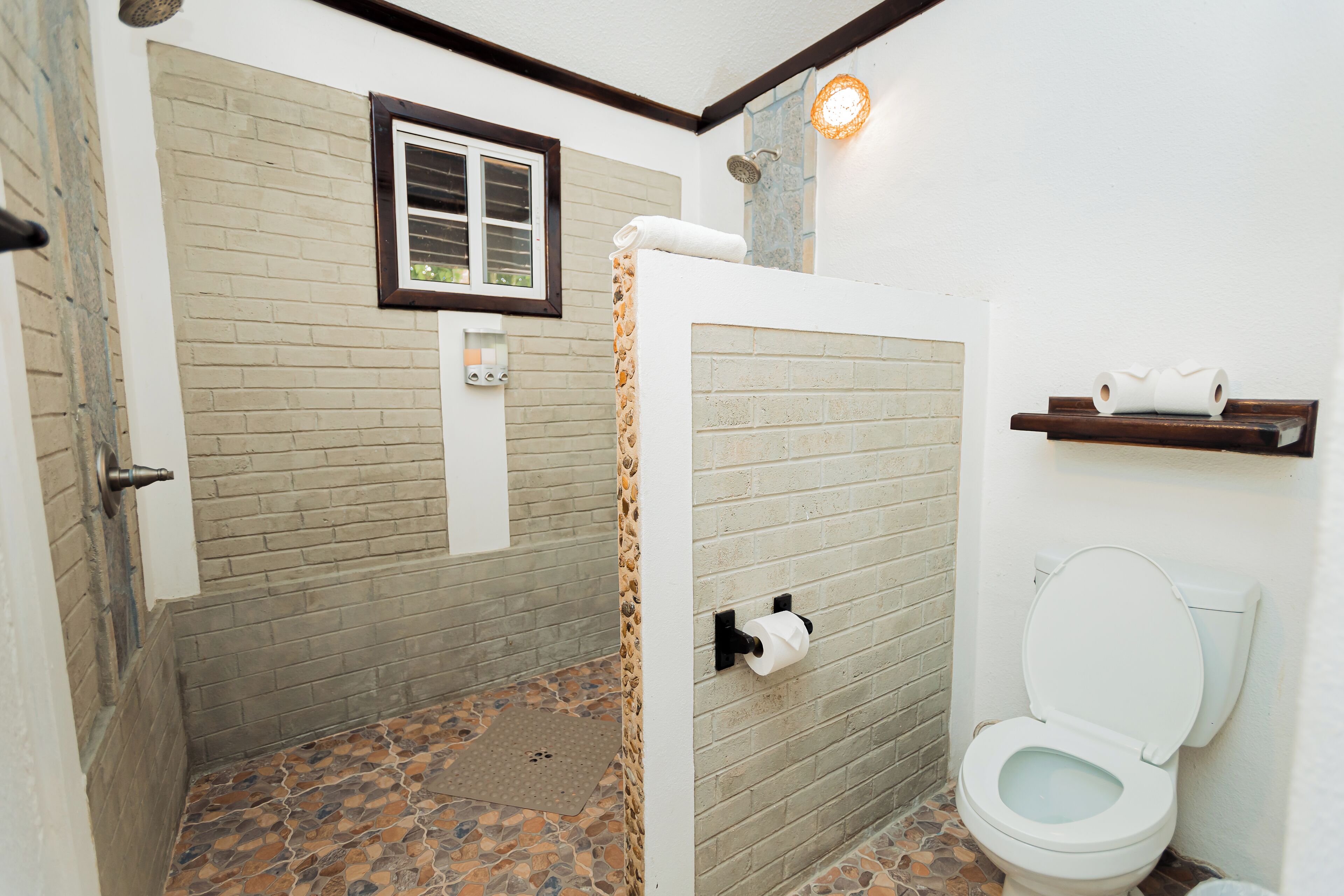 Un baño con ducha, inodoro y ventana.