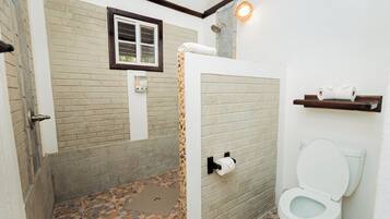 Un baño con ducha, inodoro y ventana.