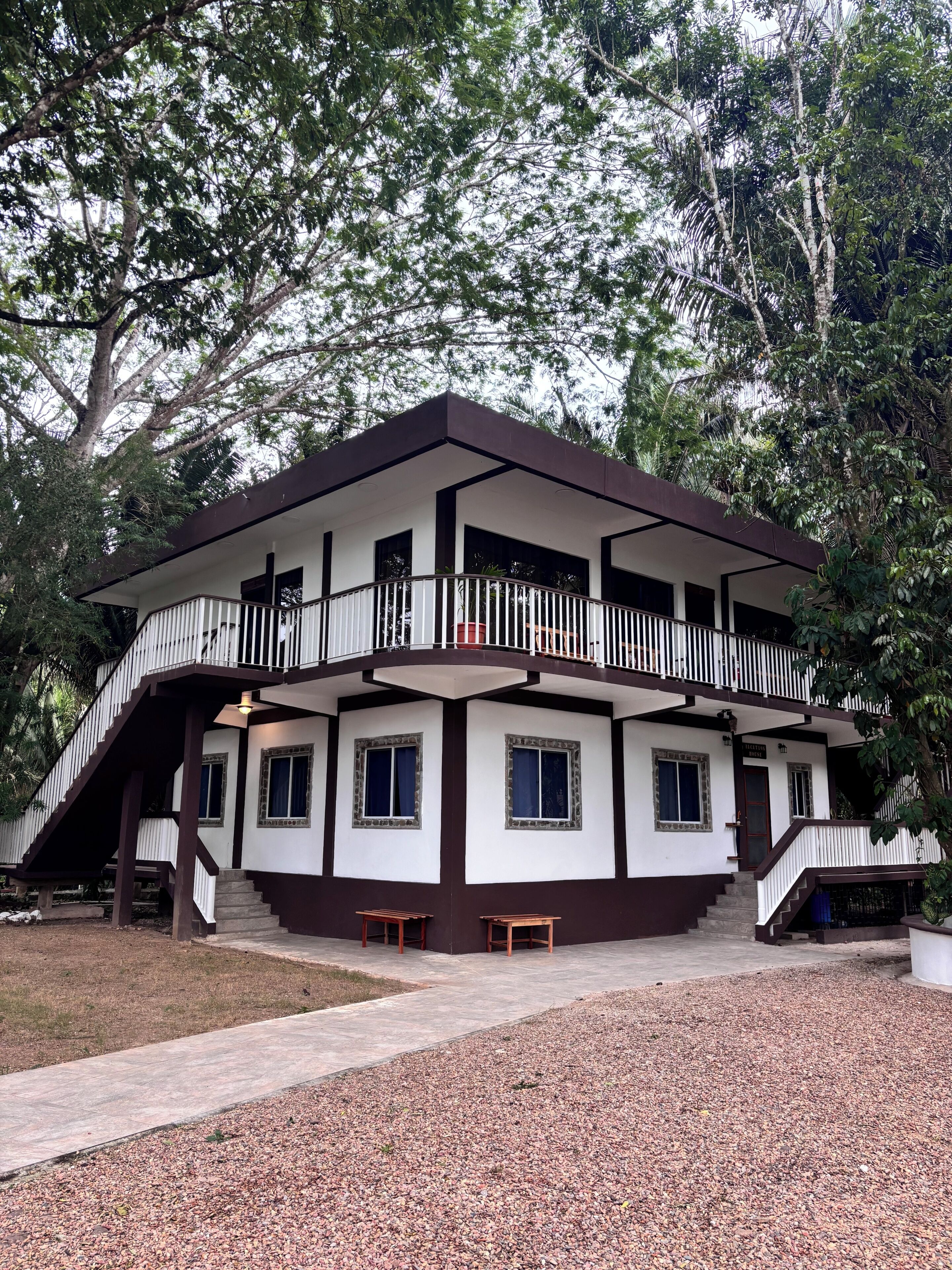 A two-story building with a balcony, multiple windows, and a staircase leading to the upper level.