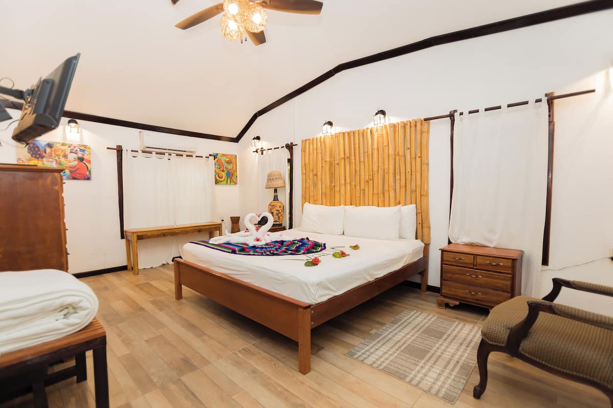 Un dormitorio con cama de madera, mesita de noche de madera, una silla, un escritorio y un ventilador de techo.
